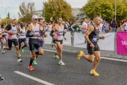Biegacze uczestniczą w maratonie, tłum kibiców na trasie.