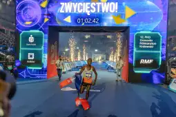 Biegacz przekracza linię mety podczas maratonu, w tle wybuchające fajerwerki.