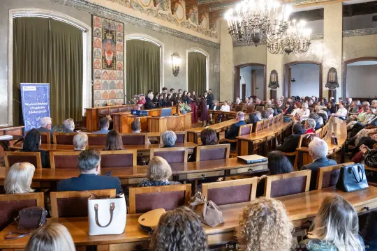 Uroczystość w sali z wystąpieniem grupy osób przed zgromadzoną publicznością.