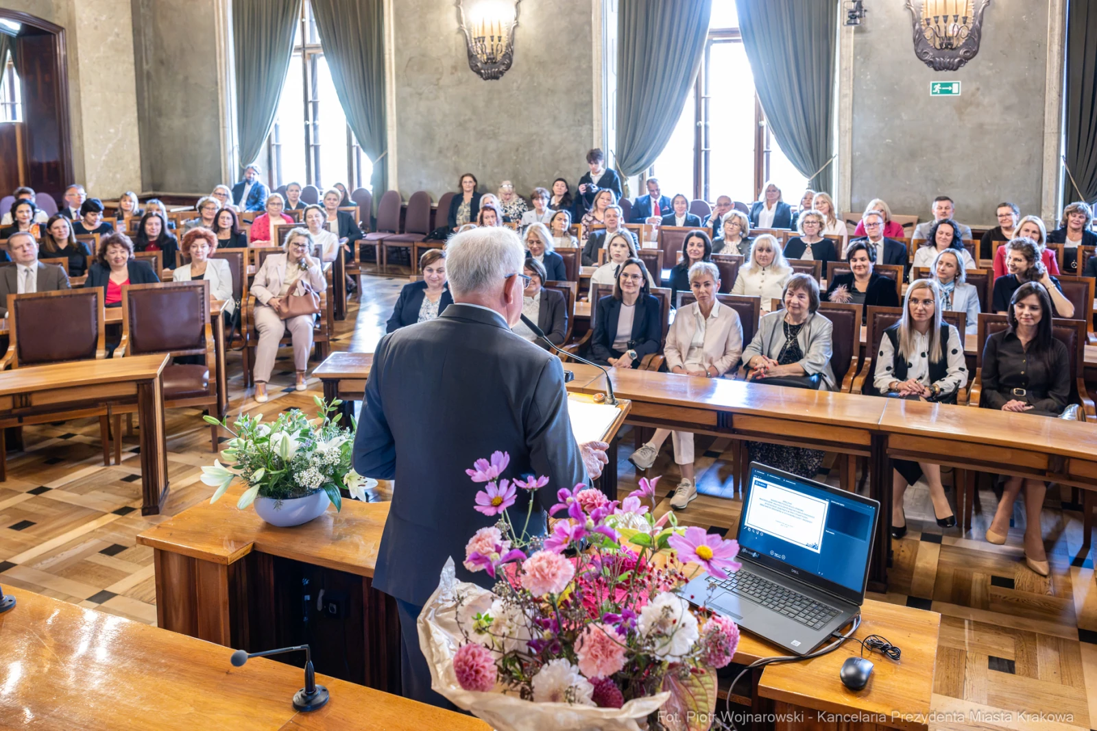 Spotkanie w sali konferencyjnej z uczestnikami i prelegentem przy mównicy. Kwiaty na stole.  Autor: Piotr Wojnarowski