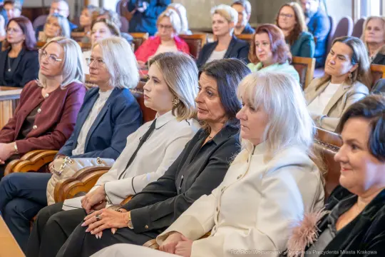 Grupa kobiet siedzących w sali, uczestniczących w wydarzeniu.