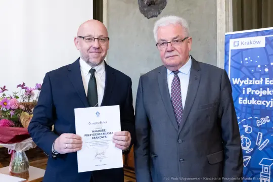 Dwaj mężczyźni trzymają dyplom nagrody Prezydenta Miasta Krakowa.