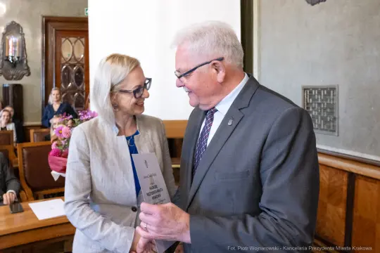 Wręczenie nagrody w sali obrad, uściski dłoni i gratulacje.
