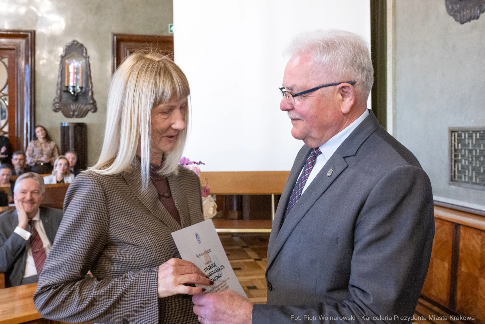 Wręczenie nagrody przez mężczyznę kobiecie w eleganckim wnętrzu.  Autor: Piotr Wojnarowski