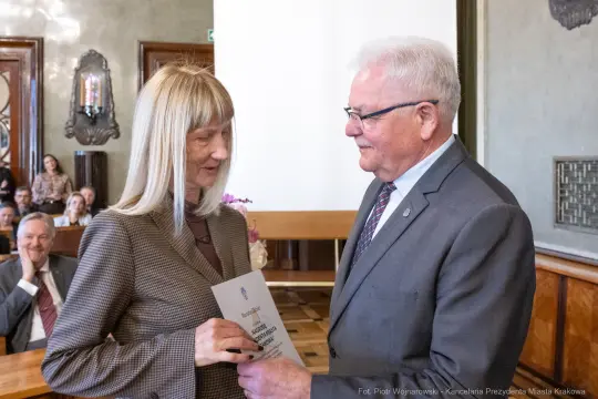 Wręczenie nagrody przez mężczyznę kobiecie w eleganckim wnętrzu.