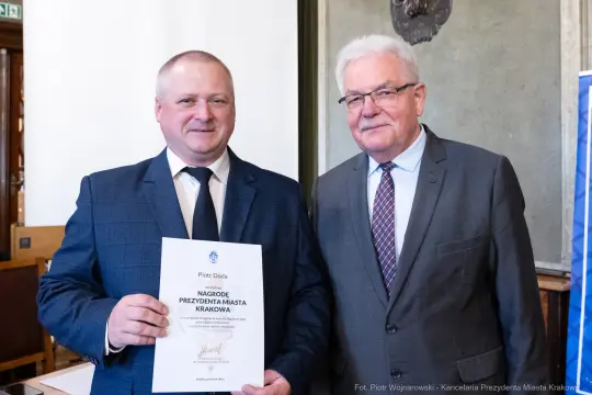 Dwóch mężczyzn trzyma dyplom nagrody Prezydenta Miasta Krakowa.