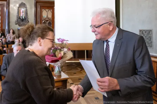 Uroczystość wręczenia nagrody, uściski dłoni i bukiet kwiatów.
