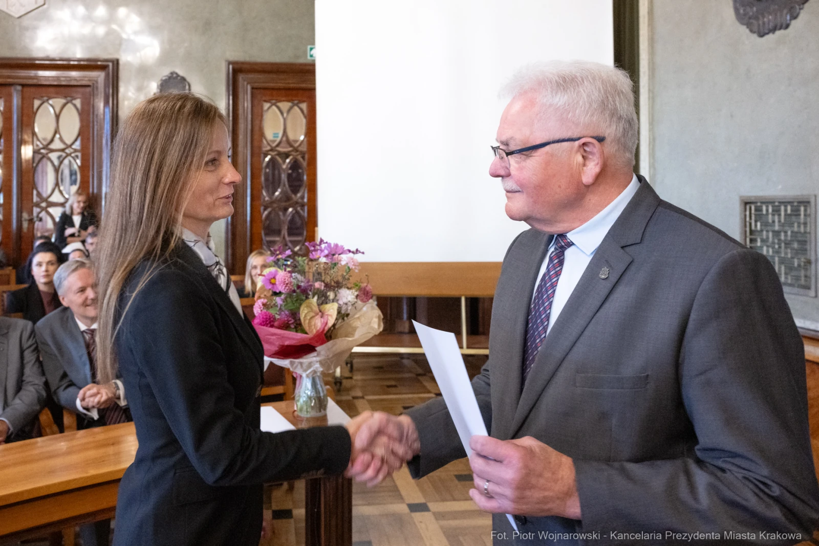 Wręczenie kwiatów i gratulacji podczas uroczystości w sali obrad.  Autor: Piotr Wojnarowski
