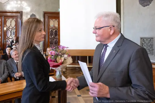 Wręczenie kwiatów i gratulacji podczas uroczystości w sali obrad.