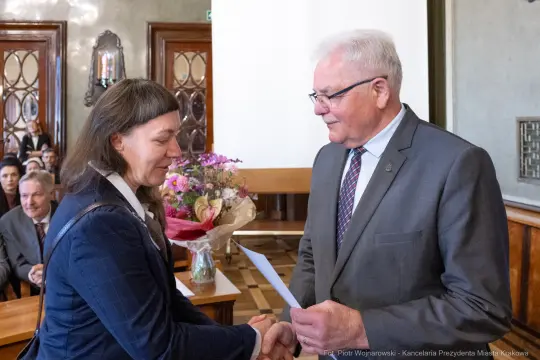 Wręczenie nagrody z bukietem kwiatów i uściskiem dłoni.