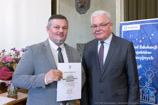 Mężczyźni trzymający dyplom nagrody Prezydenta Miasta Krakowa.