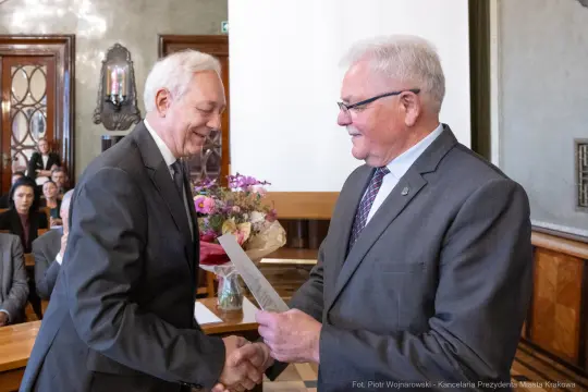 Wręczenie nagrody z bukietem kwiatów w sali urzędowej.