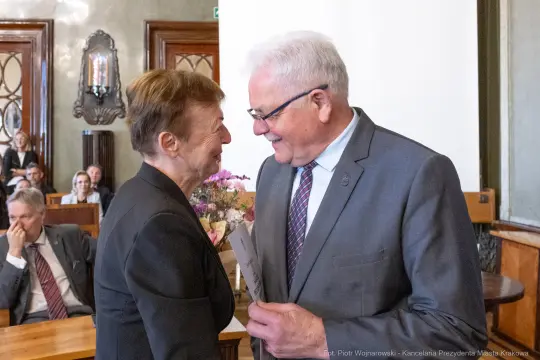 Uśmiechnięte osoby wymieniające się dokumentami w eleganckim wnętrzu.