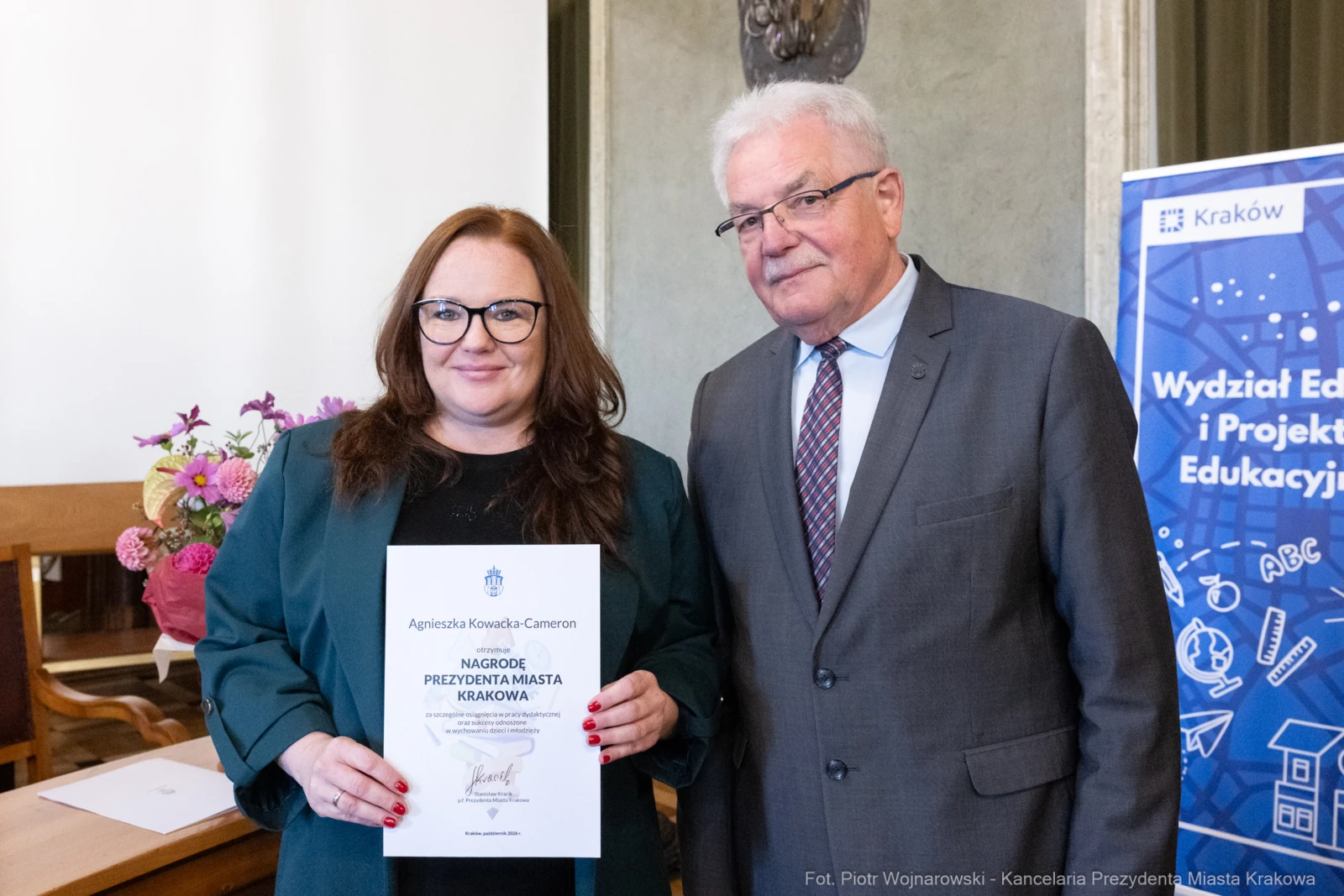 Kobieta i mężczyzna trzymają dyplom w sali z elementami dekoracyjnymi.  Autor: Piotr Wojnarowski
