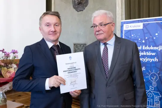 Dwaj mężczyźni trzymają dyplom nagrody Prezydenta Miasta Krakowa.