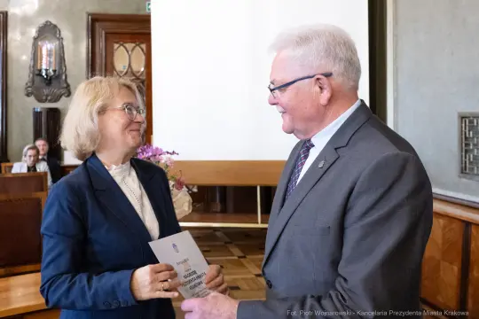 Wręczenie nagrody przez mężczyznę kobiecie w eleganckim wnętrzu.