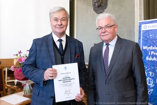 Dwaj mężczyźni trzymają dyplom nagrody Prezydenta Miasta Krakowa.