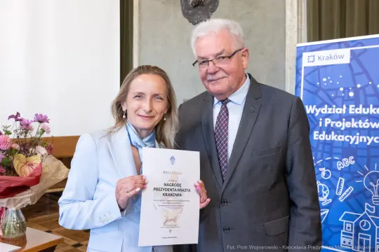 Kobieta i mężczyzna trzymają dyplom nagrody Prezydenta Miasta Krakowa.