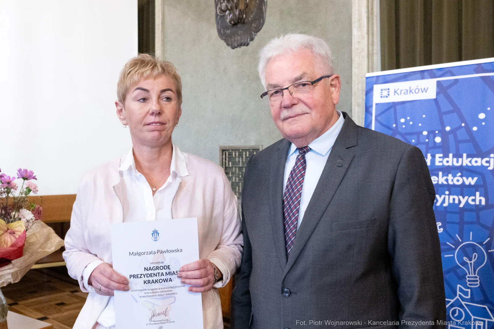 Kobieta z dyplomem i mężczyzna w garniturze, oboje uśmiechnięci.  Autor: Piotr Wojnarowski