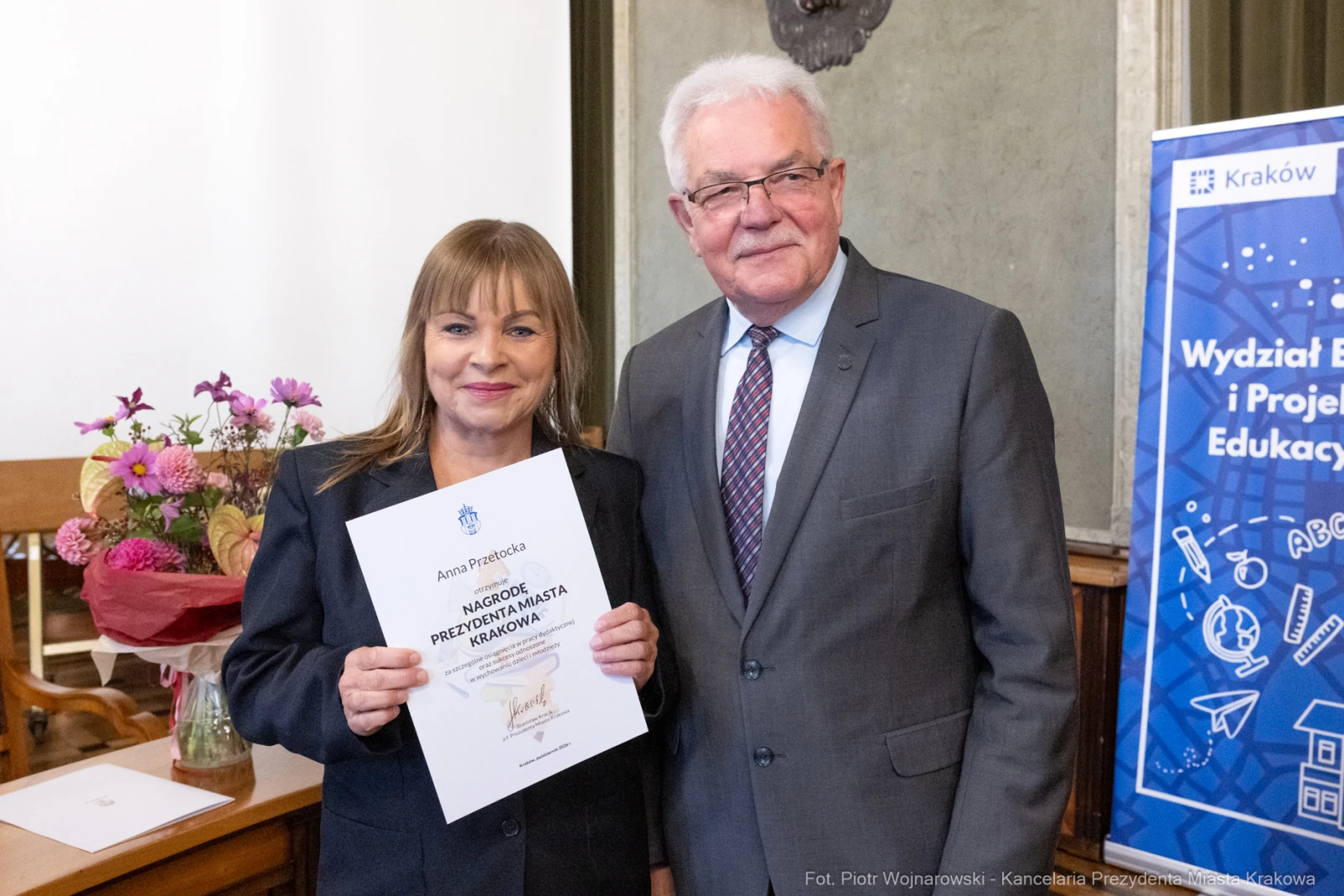 Wręczenie nagrody dla osoby z dyplomem w towarzystwie mężczyzny w garniturze.  Autor: Piotr Wojnarowski