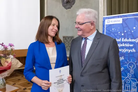 Uśmiechnięci ludzie trzymający dyplom podczas ceremonii wręczenia nagród.