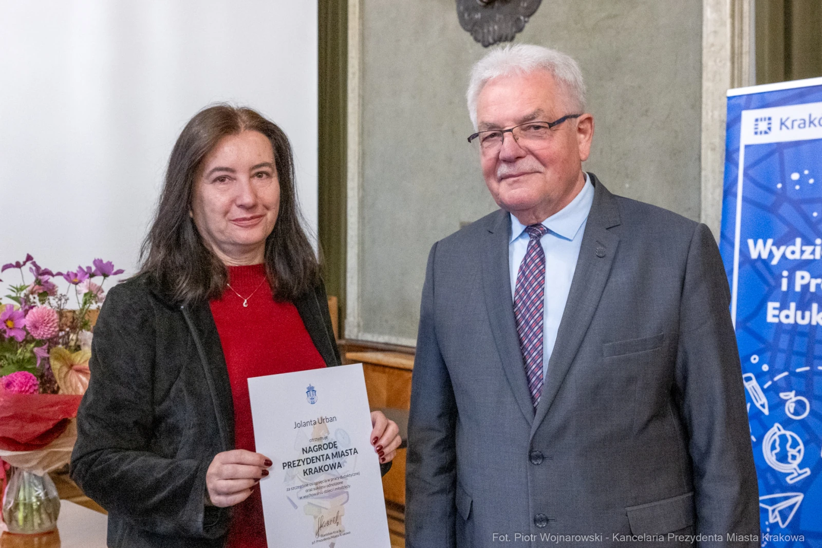 Wręczenie nagrody przez przedstawiciela miasta Krakowa. Uczestnicy wydarzenia z dokumentem w ręku.  Autor: Piotr Wojnarowski