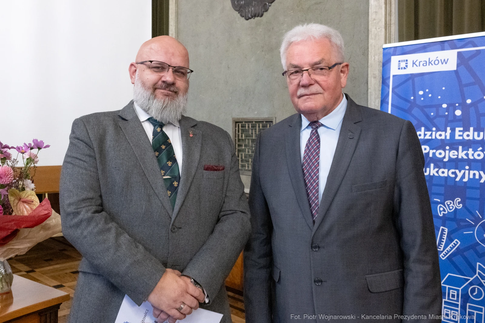Dwóch mężczyzn w formalnych strojach, stojących obok siebie w sali.  Autor: Piotr Wojnarowski