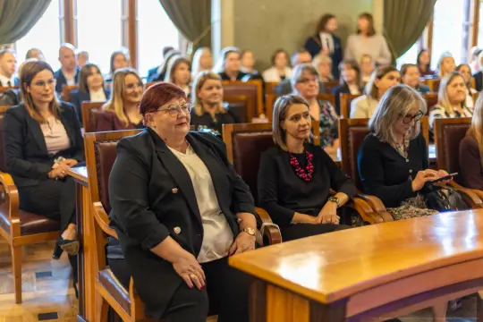 Grupa osób siedzących w sali, uczestniczących w wydarzeniu.