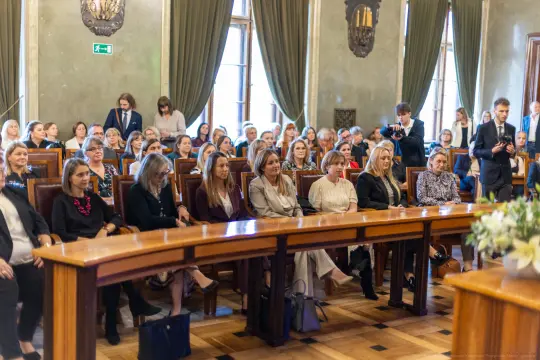 Grupa kobiet siedzących w sali konferencyjnej podczas wydarzenia.