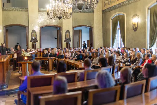 Zgromadzenie ludzi w sali konferencyjnej, prezentacja na podium.