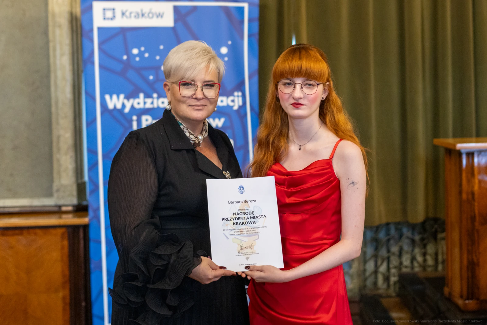 Kobieta w czarnej sukni wręcza nagrodę młodej kobiecie w czerwonej sukni.  Autor: Bogusław Świerzowski