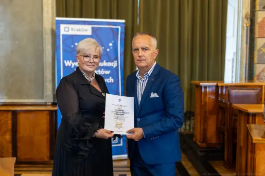 Wręczenie dyplomu w Krakowie, dwie osoby w formalnych strojach.