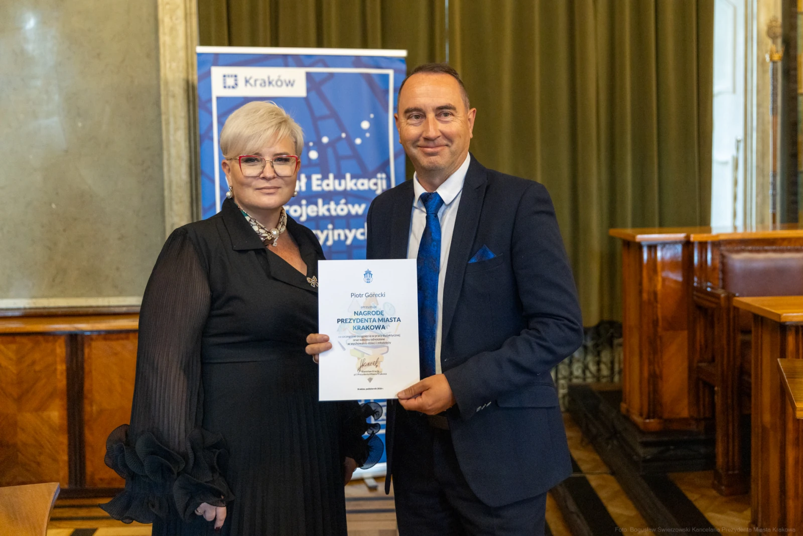 Wręczenie dyplomu w sali obrad, mężczyzna i kobieta w formalnych strojach.  Autor: Bogusław Świerzowski