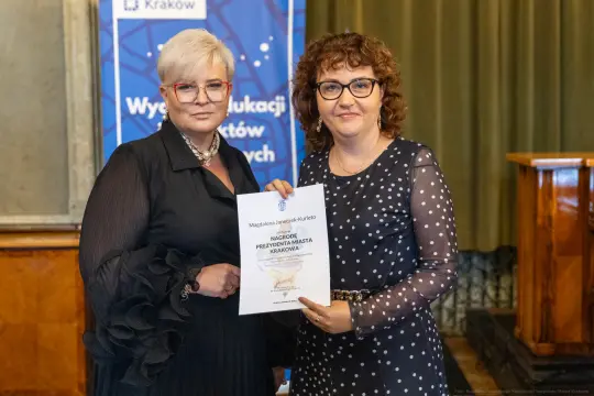 Dwie kobiety trzymają dyplom nagrody Prezydenta Miasta Krakowa.