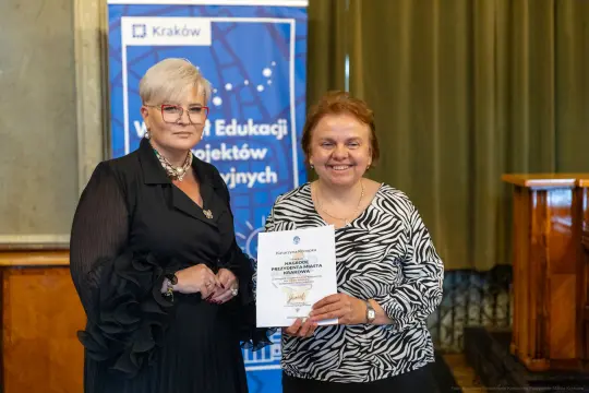 Dwie kobiety trzymające dyplom podczas uroczystości wręczenia nagród w Krakowie.