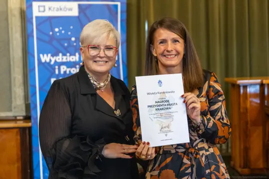 Dwie kobiety trzymają dyplom nagrody Prezydenta Miasta Krakowa.