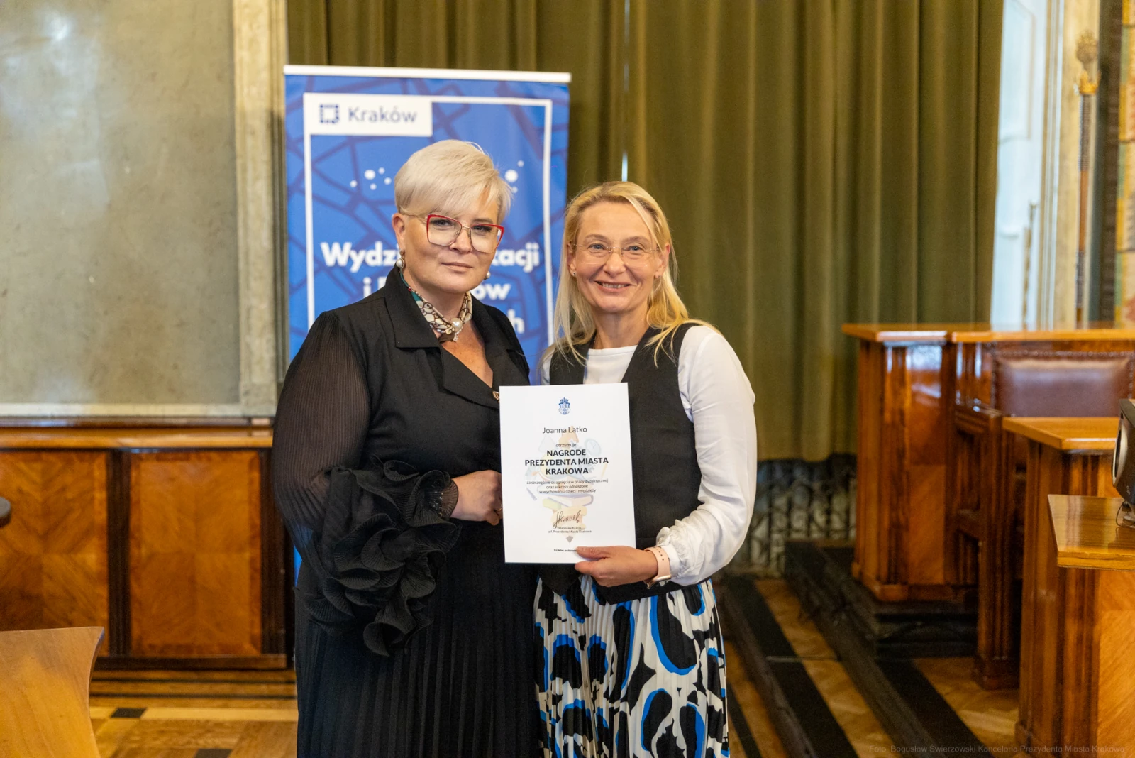Dwie kobiety trzymające dyplom w sali z drewnianymi elementami.  Autor: Bogusław Świerzowski