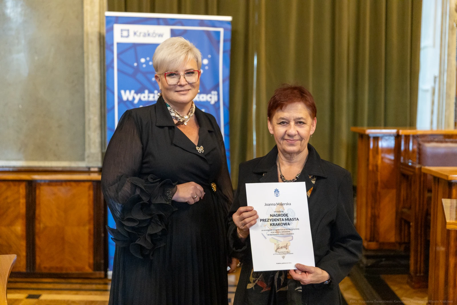 Dwie kobiety trzymają dyplom nagrody w eleganckim otoczeniu.  Autor: Bogusław Świerzowski