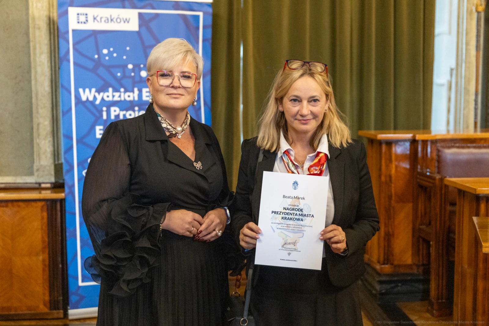 Dwie kobiety w eleganckich strojach trzymają dyplom w sali konferencyjnej.  Autor: Bogusław Świerzowski