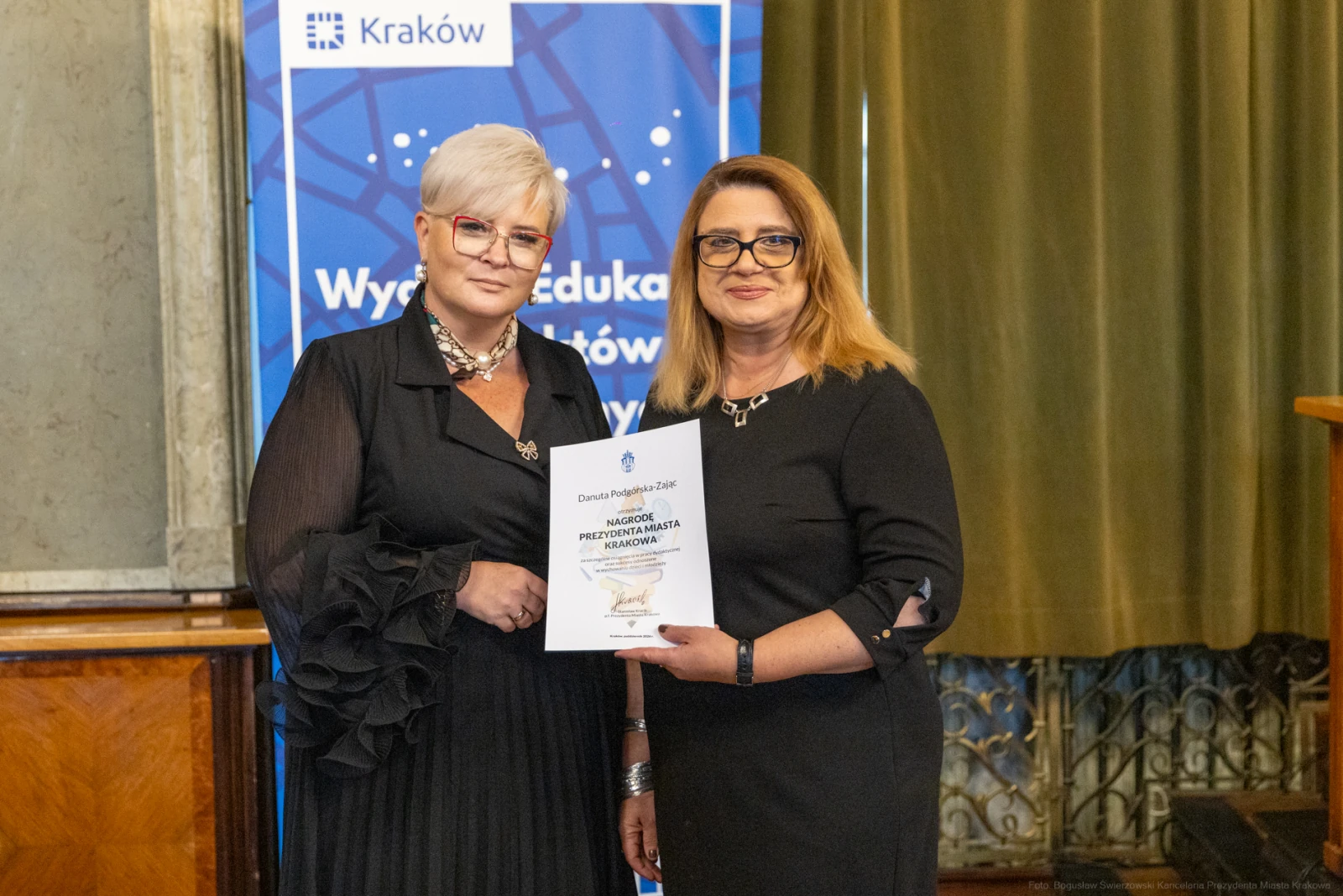 Dwie kobiety trzymające dyplom w sali z dekoracjami.  Autor: Bogusław Świerzowski