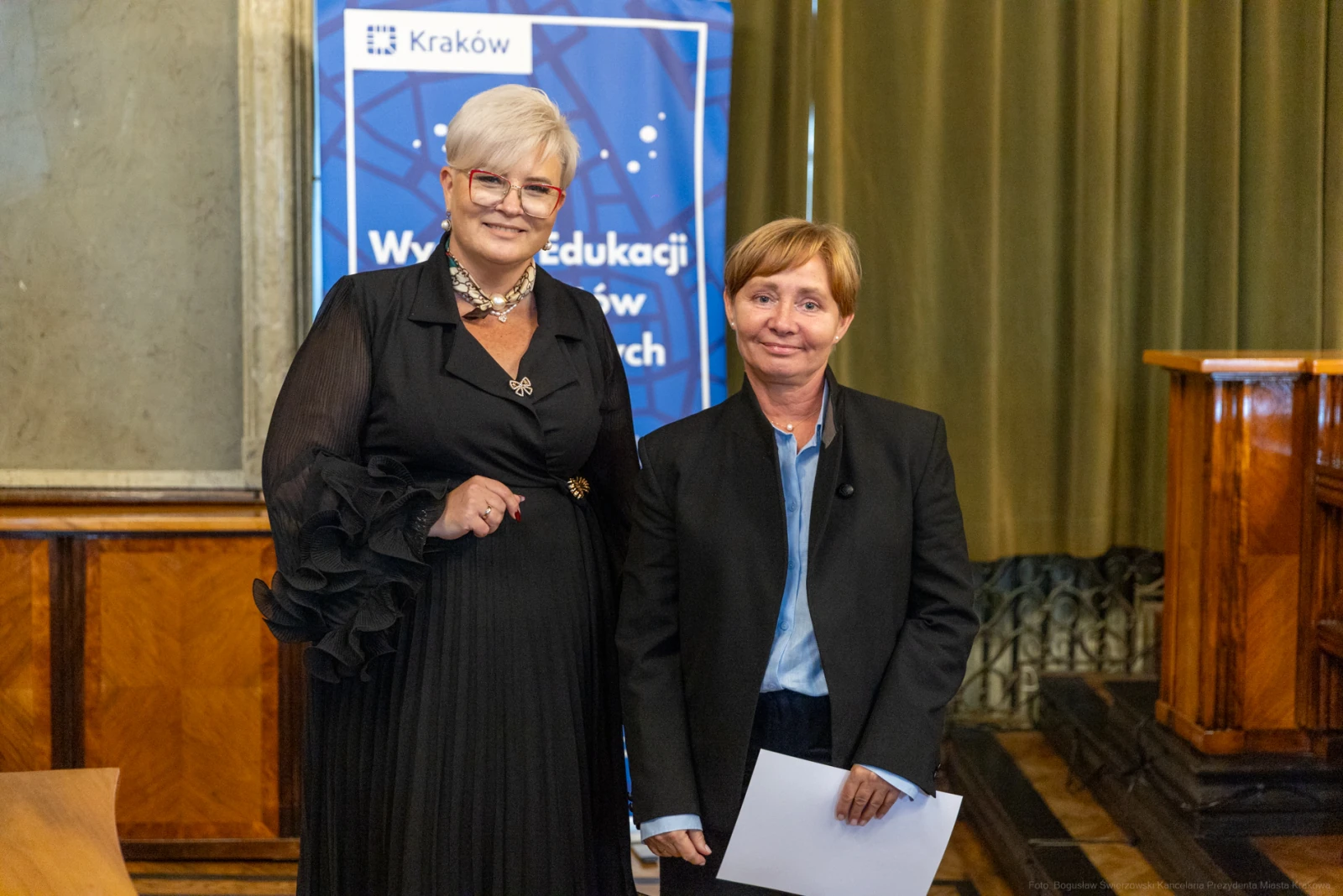 Dwie kobiety w eleganckich strojach, stojące obok siebie w sali konferencyjnej.  Autor: Bogusław Świerzowski