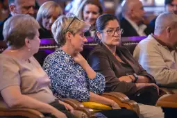 Grupa osób siedzących na widowni, wśród nich dwie kobiety w rozmowie.