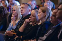 Grupa ludzi w skupieniu słuchających prelekcji.