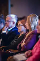 Grupa osób słuchających wykładu, z różnymi wyrazami twarzy.