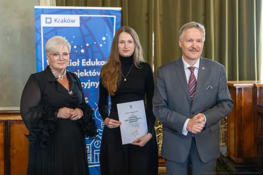 Wręczenie nagrody w Krakowie, trzy osoby pozujące z dyplomem.