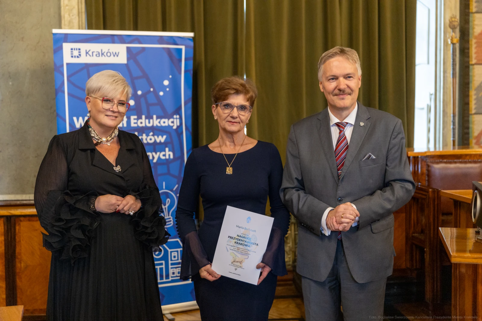 Wręczenie nagrody w dziedzinie edukacji w Krakowie, trzy osoby w formalnych strojach.  Autor: Bogusław Świerzowski