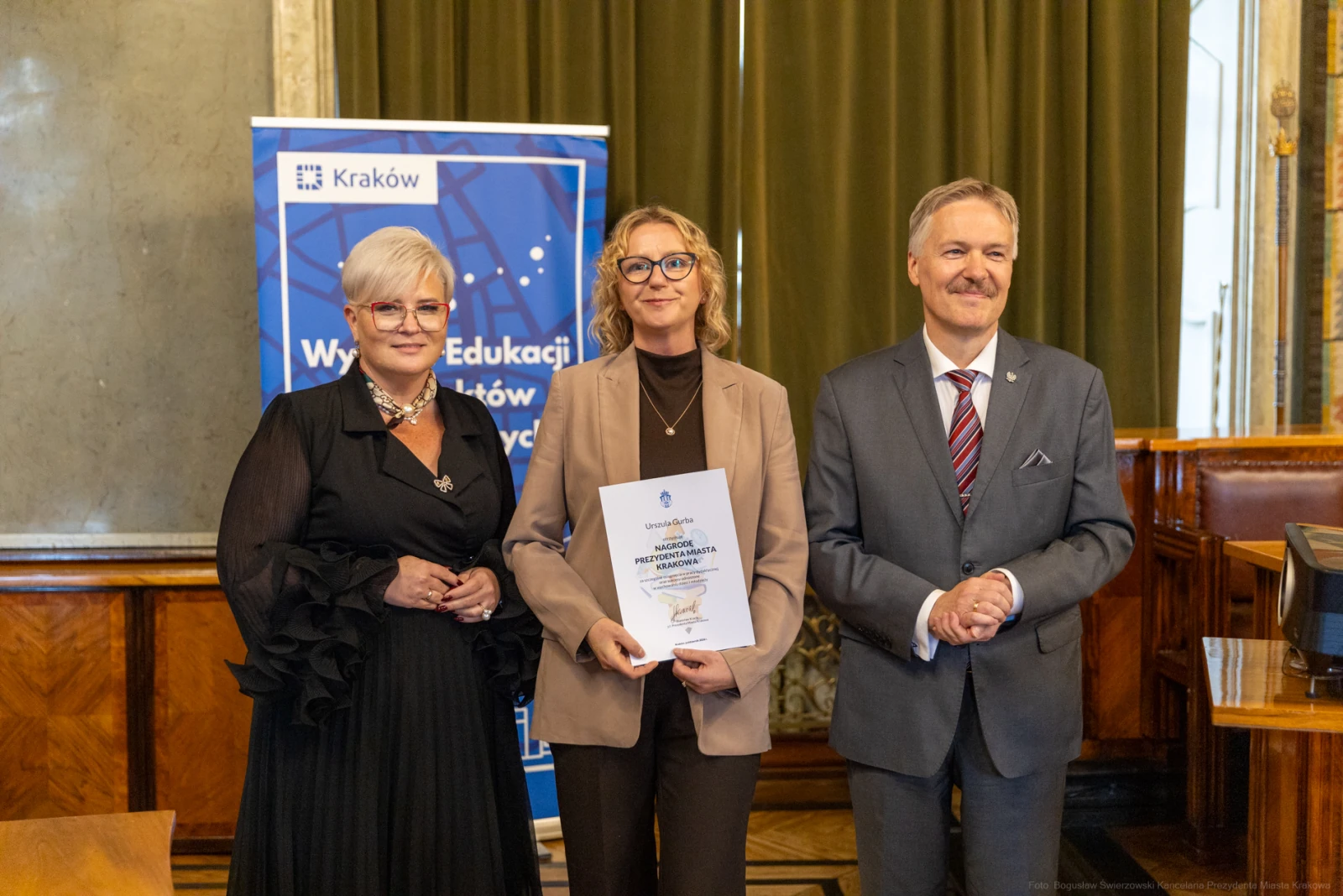 Wręczenie nagrody w dziedzinie edukacji w Krakowie. Trzy osoby pozują z dyplomem.  Autor: Bogusław Świerzowski