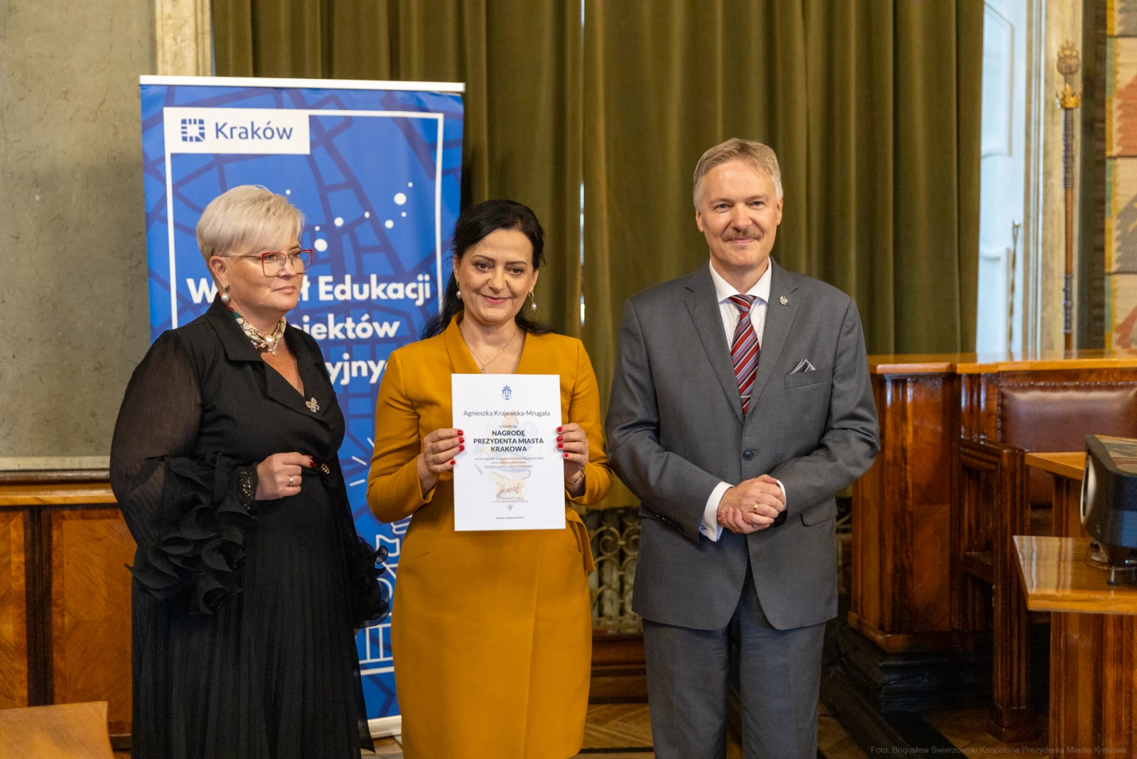 Trzy osoby w formalnych strojach trzymają dokument w sali konferencyjnej.  Autor: Bogusław Świerzowski