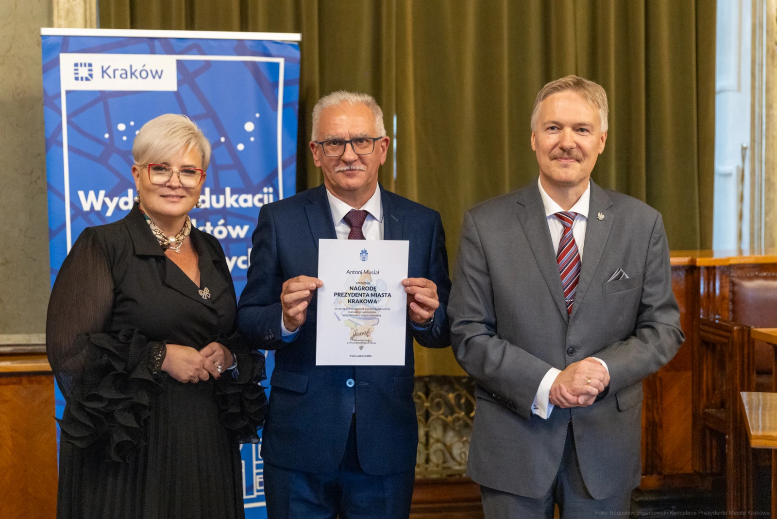 Trzech mężczyzn i kobieta trzymają dyplom w sali.  Autor: Bogusław Świerzowski