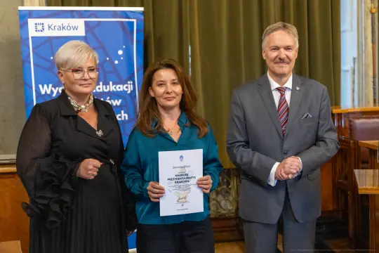 Wręczenie nagrody w Krakowie, trzej uczestnicy ceremonii z dokumentem.